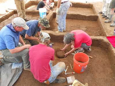 Maureen works to remove a ceramic bowl from 
                                          	its resting place at the Biggs Ford Site during the 2013 ASM Field Session