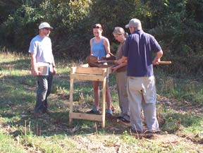 Charlie Hall looks on as student screen dirt from a test pit.